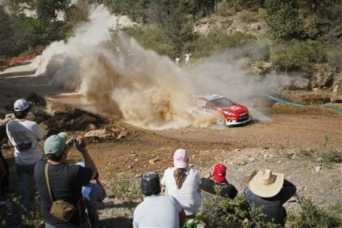 People watch M-Sport Stobart World Rally team pilot Evgeny Novikov, of Russia, and co-pilot Stephane Prevot, of Belgium, compete in the FIA's WRC Mexico Rally on the outskirts of Leon, Mexico, Friday March 4, 2011. (AP Photo/Alexandre Meneghini)