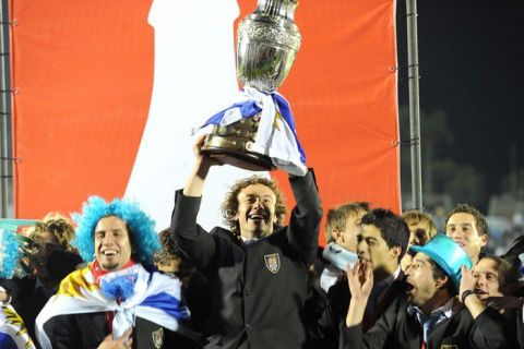 Uruguay's captain Diego Lugano (C) holds the Copa America trophy as he celebrates his team's victory with his teammates at the Centenario stadium in Montevideo on July 25, 2011. Uruguay defeated Paraguay 3-0 on on July 24 to win a record 15th Copa America with striker Diego Forlan grabbing two goals to take his international tally to 31 and complete an incredible family story. AFP PHOTO / PABLO PORCIUNCULA (Photo credit should read PABLO PORCIUNCULA/AFP/Getty Images)