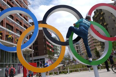 Regis Scott, a polyclinic medical team member, climbs the Olympic rings for a photo, in the Olympic Village at the 2024 Summer Olympics, Tuesday, July 23, 2024, in Paris, France. (AP Photo/Rebecca Blackwell)