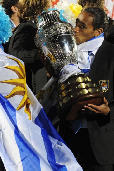 Uruguay's Alvaro Pereira kisses the Copa America trophy as he celebrates his team's victory with his teammates at the Centenario stadium in Montevideo on July 25, 2011. Uruguay defeated Paraguay 3-0 on on July 24 to win a record 15th Copa America with striker Diego Forlan grabbing two goals to take his international tally to 31 and complete an incredible family story. AFP PHOTO / PABLO PORCIUNCULA (Photo credit should read PABLO PORCIUNCULA/AFP/Getty Images)