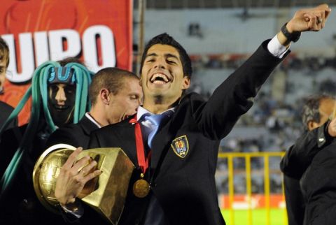 Uruguay's Luis Suarez (C) holds the Copa America trophy as he celebrates his team's victory with his teammates at the Centenario stadium in Montevideo on July 25, 2011. Uruguay defeated Paraguay 3-0 on on July 24 to win a record 15th Copa America with striker Diego Forlan grabbing two goals to take his international tally to 31 and complete an incredible family story. AFP PHOTO / PABLO PORCIUNCULA (Photo credit should read PABLO PORCIUNCULA/AFP/Getty Images)