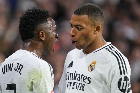 Real Madrid's Vinicius Junior, left, talks to Real Madrid's Kylian Mbappe during a Spanish La Liga soccer match between Real Madrid and Barcelona at the Santiago Bernabeu stadium in Madrid, Spain, Saturday, Oct. 26, 2024. (AP Photo/Manu Fernandez)