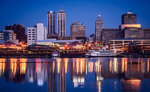 Picture of Peoria Illinois skyline at night with downtown city buildings reflection on the Illinois River and the Spirit of Peoria paddlesheel riverboat.