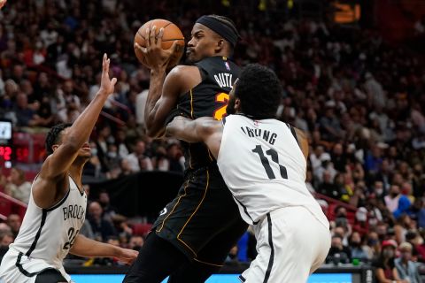 Miami Heat forward Jimmy Butler, center, goes up for a shot against Brooklyn Nets guards Kyrie Irving (11) and Cam Thomas during the second half of an NBA basketball game, Saturday, Feb. 12, 2022, in Miami. (AP Photo/Wilfredo Lee)