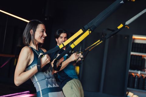 Shot of sporty couple doing trx straps exercises in a gym club.