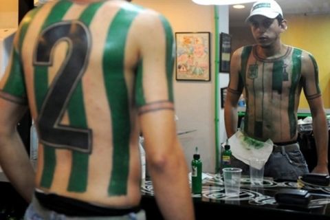 Colombian football fan Felipe Alvarez looks at the Atletico Nacional jersey tattoo --which he made in honor of footballer Andres Escobar-- during its making on October 9, 2010 at a studio in Medellin, Antioquia department, Colombia.   AFP PHOTO/Raul ARBOLEDA