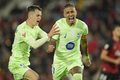 Barcelona's Raphinha, right, celebrates with Marc Casado after scoring his side's second goal from a penalty kick during a Spanish La Liga soccer match between Mallorca and Barcelona at the Son Moix stadium in Palma de Mallorca, Spain, Tuesday, Dec. 3, 2024. (AP Photo/Jose Breton)