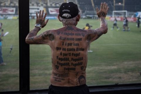 TO GO WITH AFP STORY by Javier Tovar
Brazilian football club Botafogo fan Delneri Martins Viana, a 69-year-old retired soldier, looks at the team's players warming up before a match at Sao Genario stadium in Rio de Janeiro, Brazil, on January 21, 2014. Delneri has 83 tattoos on his body dedicated to Botafogo and describes himself as the club's biggest fan.   AFP PHOTO / YASUYOSHI CHIBA