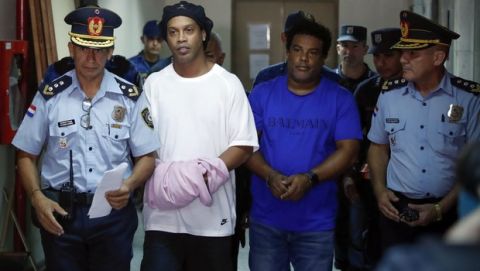 Former soccer star Ronaldinho, second from left, and his brother Roberto de Assis Moreira walks escorted by police officers to declare to judge Clara Ruiz Diaz at Justice Palace in Asuncion, Paraguay, Saturday, March 7, 2020. Ronaldinho and his brother Roberto were alleged to enter to the country with a false Paraguayan passport.(AP Photo/Jorge Saenz)