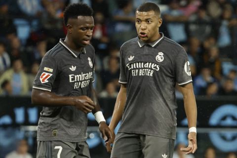 Real Madrid's Kylian Mbappe, right, speaks with Vinicius Junior during a Spanish La Liga soccer match between Celta and Real Madrid at the Balaidos, stadium in Vigo, Spain, Saturday, Oct. 19, 2024. (AP Photo/Lalo R. Villar)