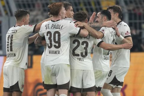 St. Pauli's team players celebrate after Eric Smith scored their side's first goal during the German Bundesliga soccer match between Borussia Dortmund and St. Pauli at the Signal-Iduna Park in Dortmund, Germany, Friday, Oct. 18, 2024. (AP Photo/Martin Meissner)