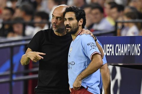 Manchester City's Ilkay Gundogan stands on the touchline with Manchester City's head coach Pep Guardiola during the group G Champions League soccer match between Sevilla and Manchester City in Seville, Spain, Tuesday, Sept. 6, 2022. (AP Photo/Jose Breton)