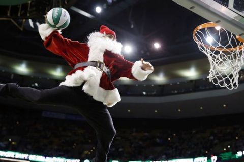 A performer in a Santa Claus costume makes a trick dunk during a timeout in the fourth quarter of an NBA basketball game between the Boston Celtics and the Minnesota Timberwolves in Boston, Monday, Dec. 16, 2013. The Celtics won 101-97. (AP Photo/Michael Dwyer)