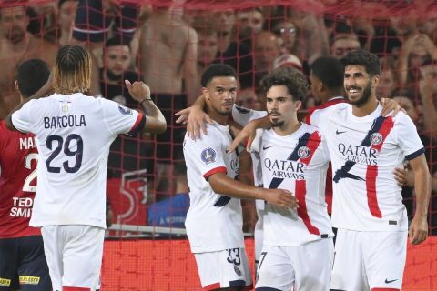 PSG's Vitinha, 2nd right, celebrates with Bradley Barcola, left, after scoring the opening goal from the penalty spot during the French League 1 soccer match between Lille and Paris Saint-Germain, in Villeneuve-d'Ascq, France, Sunday, Sept. 1, 2024. (AP Photo/Matthieu Mirville)