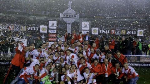 Argentina's River Plate players and staff pose with the trophy, as they celebrate winning the the Copa Libertadores final soccer match against Mexico's Tigres in Buenos Aires, Argentina, Wednesday, Aug. 6, 2015. River defeated Tigres 3-0 and became the tournament champions. (AP Photo/Ivan Fernandez)