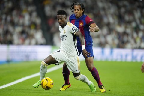 Real Madrid's Vinicius Junior, left, and Barcelona's Jules Kounde challenge for the ball during the Spanish La Liga soccer match between Real Madrid and Barcelona at the Santiago Bernabeu stadium in Madrid, Spain, Sunday, April 21, 2024. (AP Photo/Jose Breton)