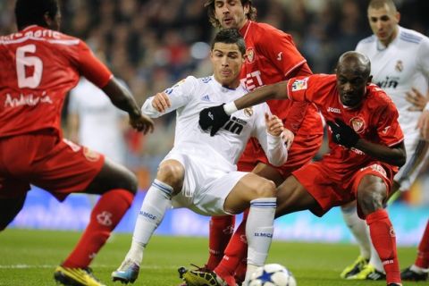 Sevilla's Sergio Sanchez (background) and Didier Zokora (R) challenge Real Madrid's Cristiano Ronaldo (C) during their Spanish King's Cup semi-final second leg soccer match at the Santiago Bernabeu stadium in Madrid February 2, 2011.    REUTERS/Felix Ordonez (SPAIN - Tags: SPORT SOCCER)