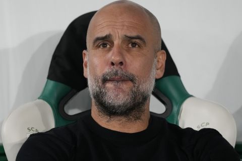 Manchester City's head coach Pep Guardiola sits before the UEFA Champions League opening phase match between Sporting and Manchester City in Lisbon, Portugal, Tuesday, Nov. 5, 2024. (AP Photo/Armando Franca)