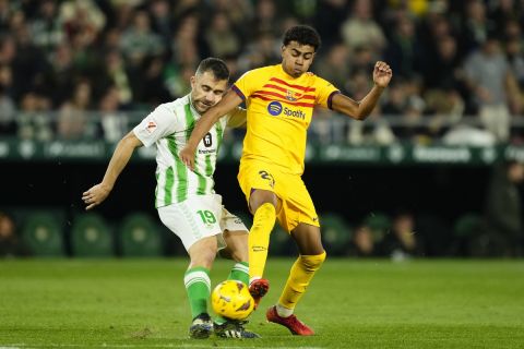 Betis' Sokratis Papastathopoulos, left, challenges for the ball with Barcelona's Lamine Yamal during a Spanish La Liga soccer match between Betis and Barcelona at the Benito Villamarin stadium in Seville, Spain, Sunday, Jan. 21, 2024. (AP Photo/Jose Breton)