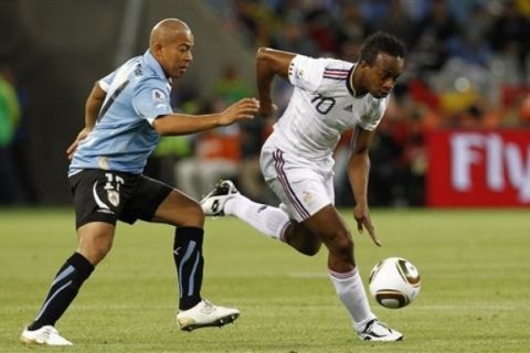 France's Sidney Govou, right, is tackled by Uruguay's Edigio Arevalo Rios, left, during the World Cup group A soccer match between Uruguay and France in Cape Town, South Africa, Friday, June 11, 2010.  (AP Photo/Francois Mori)