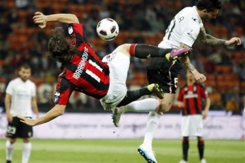 AC Milan forward Zlatan Ibrahimovic, left, of Sweden, is airborne as he goes for an acrobatic kick with Palermo Chilean forward Mauricio Pinilla Ferrera during their Italian Cup, first-leg, semifinal soccer match, at the San Siro stadium in Milan, Italy, Wednesday, April 20, 2011. (AP Photo/Antonio Calanni)