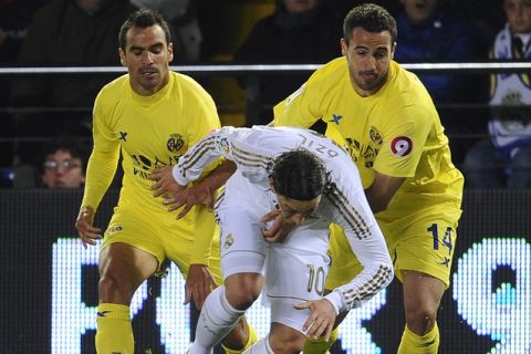 Real Madrid's German midfielder Mesut Ozil (C) vies with Villarreal's defender Angel Lopez (L) and Villarreal's defender Mario Gaspar (R) during their Spanish league football match Villarreal vs Real Madrid on March 21, 2012 at the Madridgal stadium in Villarreal. AFP PHOTO/ PIERRE-PHILIPPE MARCOU (Photo credit should read PIERRE-PHILIPPE MARCOU/AFP/Getty Images)