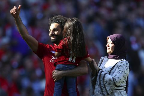 Liverpool's Mohamed Salah, accompanied by his wife Maggi greets supporters while holding his daughter Makka, age 5, at the end of the English Premier League soccer match between Liverpool and Wolverhampton Wanderers at the Anfield stadium in Liverpool, England, Sunday, May 12, 2019. Despite a 2-0 win over Wolverhampton Wanderers, Liverpool missed out on becoming English champion for the first time since 1990 because title rival Manchester City beat Brighton 4-1. (AP Photo/Dave Thompson)