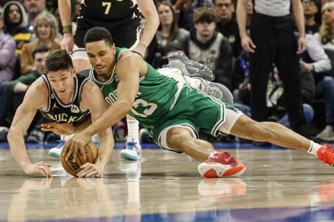 Milwaukee Bucks guard Grayson Allen (12) and Boston Celtics guard Malcolm Brogdon (13) reach for a loose ball during an NBA basketball game, Tuesday, Feb. 14, 2023, in Milwaukee. (AP Photo/Jeffrey Phelps)