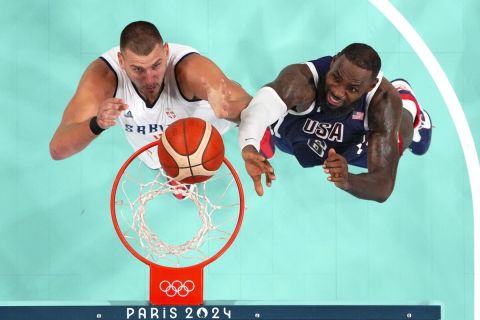 Nikola Jokic, left, of Serbia, and LeBron James, of the United States, reach for a rebound at the 2024 Summer Olympics, Sunday, July 28, 2024, in Villeneuve-d'Ascq, France. (Evelyn Hockstein/Pool Photo via AP)