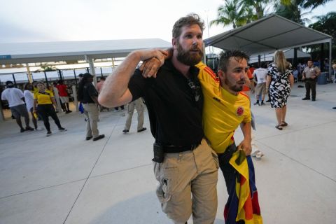 A security agent assists a fan who was waiting to enter the stadium prior to the Copa America final soccer match between Argentina and Colombia, in Miami Gardens, Fla., Sunday, July 14, 2024. (AP Photo/Lynne Sladky)