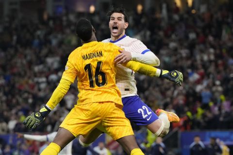 Theo Hernandez of France, right, celebrates with goalkeeper Mike Maignan after scores the winning goal to defeat Portugal during a quarter final match at the Euro 2024 soccer tournament in Hamburg, Germany, Friday, July 5, 2024. (AP Photo/Hassan Ammar)