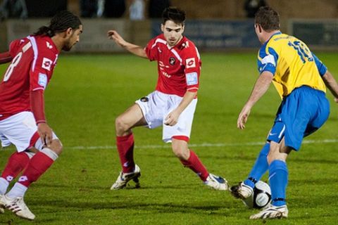 Scott Taylor considers his options as he looks to take the ball past Fakinos and Marwa