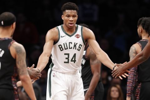 Giannis Antetokounmpo slaps hands with teammates during the first half of an NBA basketball game against the Brooklyn Nets, Monday, Feb. 4, 2019, in New York. (AP Photo/Kathy Willens)