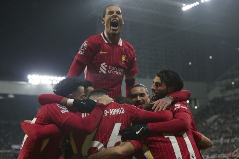 Liverpool's Virgil van Dijk, top, celebrates with teammates after Mohamed Salah scored his side's third goal during the English Premier League soccer match between Newcastle and Liverpool, at St. James Park in Newcastle, England, Wednesday, Dec 4, 2024. (AP Photo/Ian Hodgson)