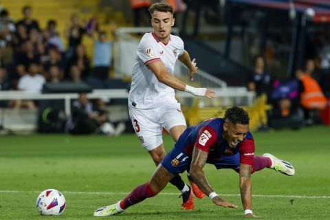 Barcelona's Raphinha, front, duels for the ball with Sevilla's Adria Pedrosa during a Spanish La Liga soccer match between Barcelona and Sevilla, at the Olympic Stadium of Montjuic in Barcelona, Spain, Friday, Sept. 29, 2023. (AP Photo/Joan Monfort)