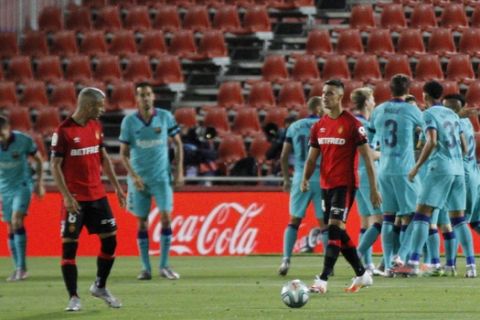 FC Barcelona players celebrate Arturo Vidal's goal during the Spanish La Liga soccer match between Mallorca and FC Barcelona at Son Moix Stadium in Palma de Mallorca, Saturday, June 13, 2020. With virtual crowds, daily matches and lots of testing for the coronavirus, soccer is coming back to Spain. The Spanish league resumes this week more than three months after it was suspended because of the COVID-19 pandemic. (AP Photo/Francisco Ubilla)