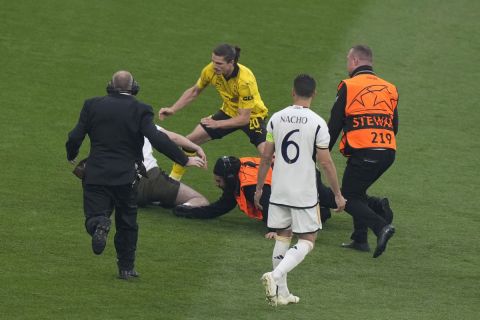 Dortmund's Marcel Sabitzer, second left, and stewards chase a pitch invader during the Champions League final soccer match between Borussia Dortmund and Real Madrid at Wembley stadium in London, Saturday, June 1, 2024. (AP Photo/Alastair Grant)