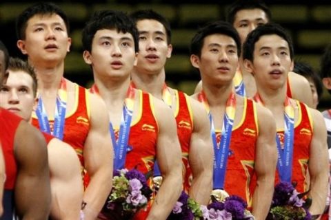 China's gymnasts, from left, Chen Yibing, Feng Zhe,  Yan Mingyong, Teng Haibin, Zou Kai and Zhang Chenglong, partly seen in back, listen to the national anthem during the awarding ceremony at the men's team final at  the Artistic Gymnastics World Championships in Tokyo, Japan, Wednesday, Oct. 12, 2011. (AP Photo/Bullit Marquez)