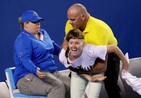 A political protester, center,  is caught by a security guard during the men's singles final between Andy Murray of Britain and Novak Djokovic of Serbia at the Australian Open tennis championship in Melbourne, Australia, Sunday, Feb. 1, 2015. (AP Photo/Rob Griffith) ORG XMIT: MEL205