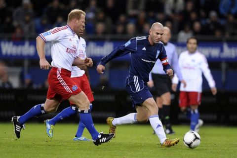 Former French international Zinedine Zidane (R) runs with the ball during the "Match Against Poverty" friendly charity football in support of Horn of Africa famine relief led by the United Nations Development Programme (UNDP) between an all-star side of Hamburger SV and a selection of other International players including UNDP Goodwill Ambassadors Ronaldo and Zidane in the northern German city of Hamburg on December 13, 2011.  AFP PHOTO / OLIVER HARDT (Photo credit should read OLIVER HARDT/AFP/Getty Images)