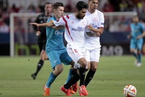 GRA469. SEVILLA, 16/04/2015.- El defensa francés del Sevilla Benoît Trémoulinas (c) lucha un balón con el centrocampista del Zenit Aleksandr Ryazantsev (i), durante el partido de ida de los cuartos de final de la Liga Europa disputado esta noche en el estadio Sánchez Pizjuán. EFE/Paco Puentes