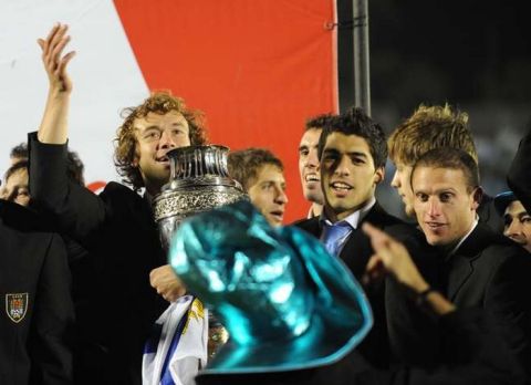 Uruguayan national soccer team players Diego Lugano (L), Luis Suarez (C) and Diego Perez celebrate with the cup at the Centenario stadium in Montevideo, after winning the Copa America tournament on July 25, 2011. Uruguay beat Paraguay 3-0 in the final, making it their 15th triumph in the Copa America tournament and becoming the leading tournament winner. 
AFP PHOTO / PABLO PORCIUNCULA (Photo credit should read PABLO PORCIUNCULA/AFP/Getty Images)