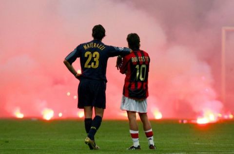 Inter Milan's Marco Materazzi  (L) and AC Milan's Manuel Rui Costa waits on the pitch as supporters throw flares onto the pitch during their Champions League quarter-final second leg soccer match at the San Siro Stadium in Milan April 12, 2005.                             REUTERS/Stefano Rellandini