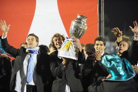 Uruguay's captain Diego Lugano (C) holds the Copa America trophy as he celebrates his team's victory with his teammates at the Centenario stadium in Montevideo on July 25, 2011. Uruguay defeated Paraguay 3-0 on on July 24 to win a record 15th Copa America with striker Diego Forlan grabbing two goals to take his international tally to 31 and complete an incredible family story. AFP PHOTO / PABLO PORCIUNCULA (Photo credit should read PABLO PORCIUNCULA/AFP/Getty Images)