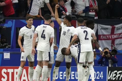 England's Jude Bellingham, centre, clenching his fist as he celebrates with teammates after scoring the opening goal during a Group C match between Serbia and England at the Euro 2024 soccer tournament in Gelsenkirchen, Germany, Sunday, June 16, 2024. (AP Photo/Frank Augstein)