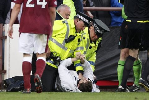 Police hold down a man after he tried to attack Celtic manager Neil Lennon in the dugout area during their Scottish Premier league soccer match against Hearts at Tynecastle Stadium in Edinburgh, Scotland May 11, 2011. REUTERS/David Moir (BRITAIN - Tags: SPORT SOCCER)