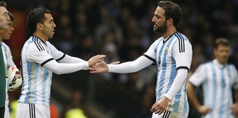 Carlos Tevez of Argentina, left, comes on to replace Gonzalo Higuain during the International Friendly soccer match at Old Trafford Stadium, Manchester, England, Tuesday Nov. 18, 2014. (AP Photo/Jon Super)  