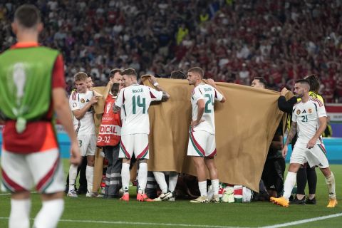 Players hold a blanket as medical personnel treat Hungary's Barnabas Varga during a Group A match between Scotland and Hungary at the Euro 2024 soccer tournament in Stuttgart, Germany, Sunday, June 23, 2024. (AP Photo/Antonio Calanni)