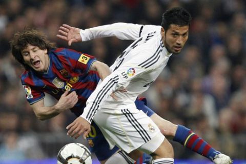 Barcelona's Lionel Messi (L) is tackled by Real Madrid's Ezequiel Garay during their Spanish first division soccer match at Santiago Bernabeu stadium in Madrid April 10 2010.  REUTERS/Paul Hanna (SPAIN - Tags: SPORT SOCCER IMAGES OF THE DAY)