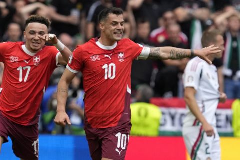 Switzerland's Kwadwo Duah, left, celebrates after scoring his side's opening goal besides team mates Ruben Vargas, center, and Granit Xhaka during a Group A match between Hungary and Switzerland at the Euro 2024 soccer tournament in Cologne, Germany, Saturday, June 15, 2024. (AP Photo/Darko Vojinovic)